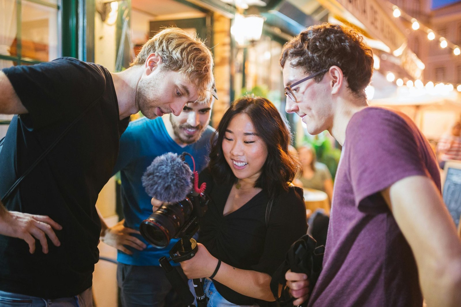 Group of friends reviewing footage on a camera during a street photography session in Lisbon.