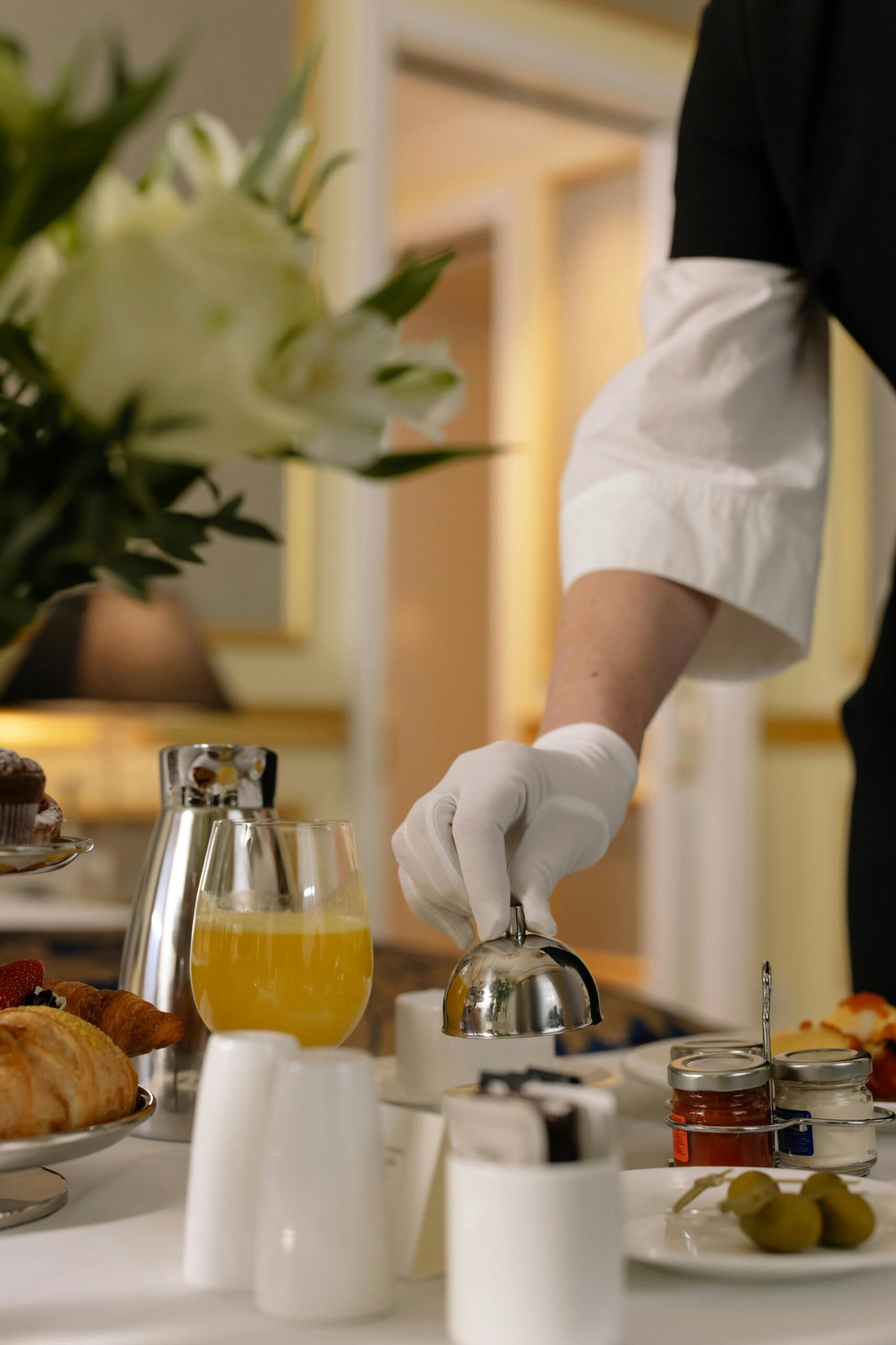 Deluxe room service breakfast arrangement with pastries, juice, and elegant table setting in a luxury hotel room.